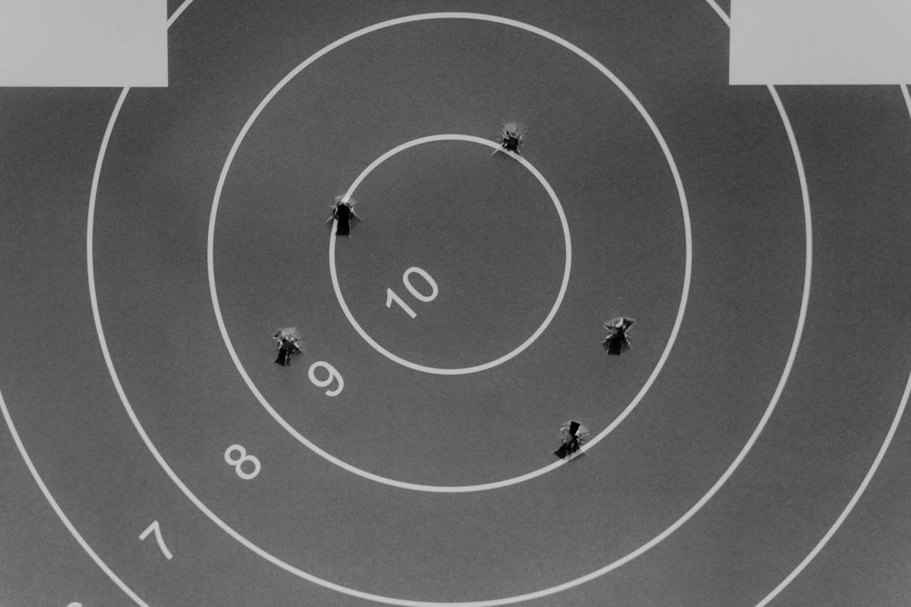 services-01 Black and white image of a shooting target with bullet holes.