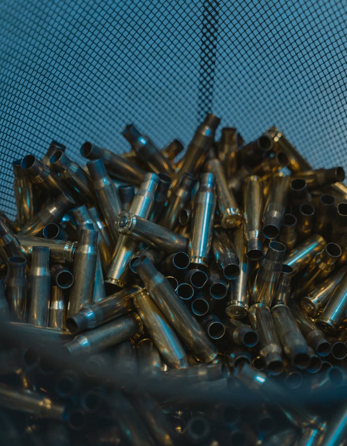 our-experience A collection of metallic bullet casings in a mesh container, reflecting industrial ambiance.